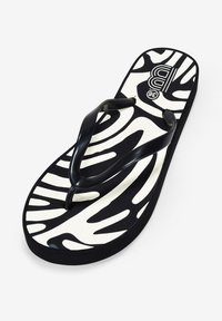 Chanclas de plástico negras con un diseño de estampado de cebra sobre un fondo crema. Diseñadas con una suela plana y con tiras en forma de Y.