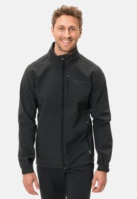Čierna softshell bunda s vysokým golierom, predným zipsom a bočnými vreckami. Obsahuje logo na hrudi. Textúrovaná, vodoodolná tkanina.