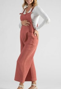 Roze geweven jumpsuit met wijde pijpen, verstelbare bandjes en zakken. Wafelstructuur en een relaxte pasvorm, gecombineerd met een top met lange mouwen.