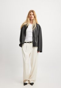 Juodas odinis užtrauktukas striukė, balta prigludusi palaidinė, plisuotos kreminės kelnės, juodas diržas, smaili juoda avalynė. Paprastas dizainas, laisvas siluetas.