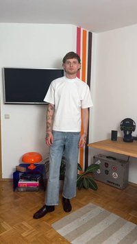 White short-sleeve T-shirt, light blue wide-leg jeans, and dark brown shoes. Background features a TV, orange lamp, and plants.