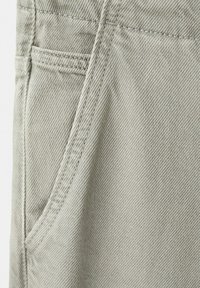 Tissu en denim gris clair avec des coutures détaillées et une poche avant sur un pantalon.