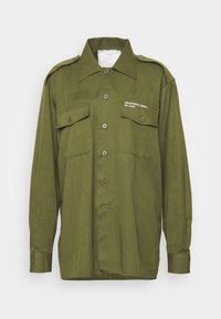 Camicia verde oliva con bottoni, realizzata in tessuto leggero, dotata di due tasche sul petto, spalline e testo "DESIGNER, REMIX Re-made".