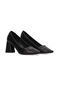 Zapatos de tacón alto de cuero negro con puntera puntiaguda y tacón grueso. Textura suave y minimalismo en los detalles de la parte superior.