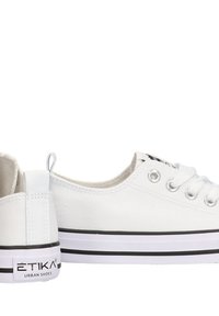 Zapatillas de lona blancas con puntera redonda, cierre de cordones en la parte delantera y detalles de raya negra en la suela. Logotipo en el talón y en el lateral. Suela de goma plana.