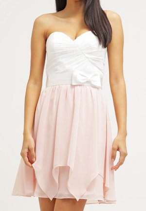 Abito senza spalline con corpetto bianco plissettato e fiocco decorativo, che sfuma in una gonna di chiffon rosa fluente con orlo a strati.