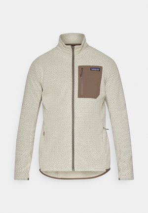 Light beige jacket with a textured pattern, a brown zippered chest pocket, and contrasting brown zipper details. Long sleeves, stand-up collar.