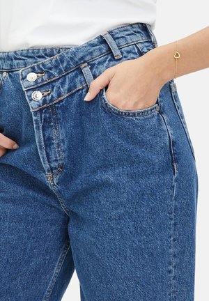 Denim-Jeans in einem mittleren Blauton mit hoher Taille, zwei Knöpfen und sichtbaren Nähten. Sie verfügen über eine Fronttasche und einen strukturierten Stoff.