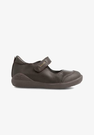 Zapato Mary Jane de cuero marrón con una correa de velcro, puntera redondeada y tapa de puntera texturizada. Presenta una suela de goma y un logotipo grabado en el talón.