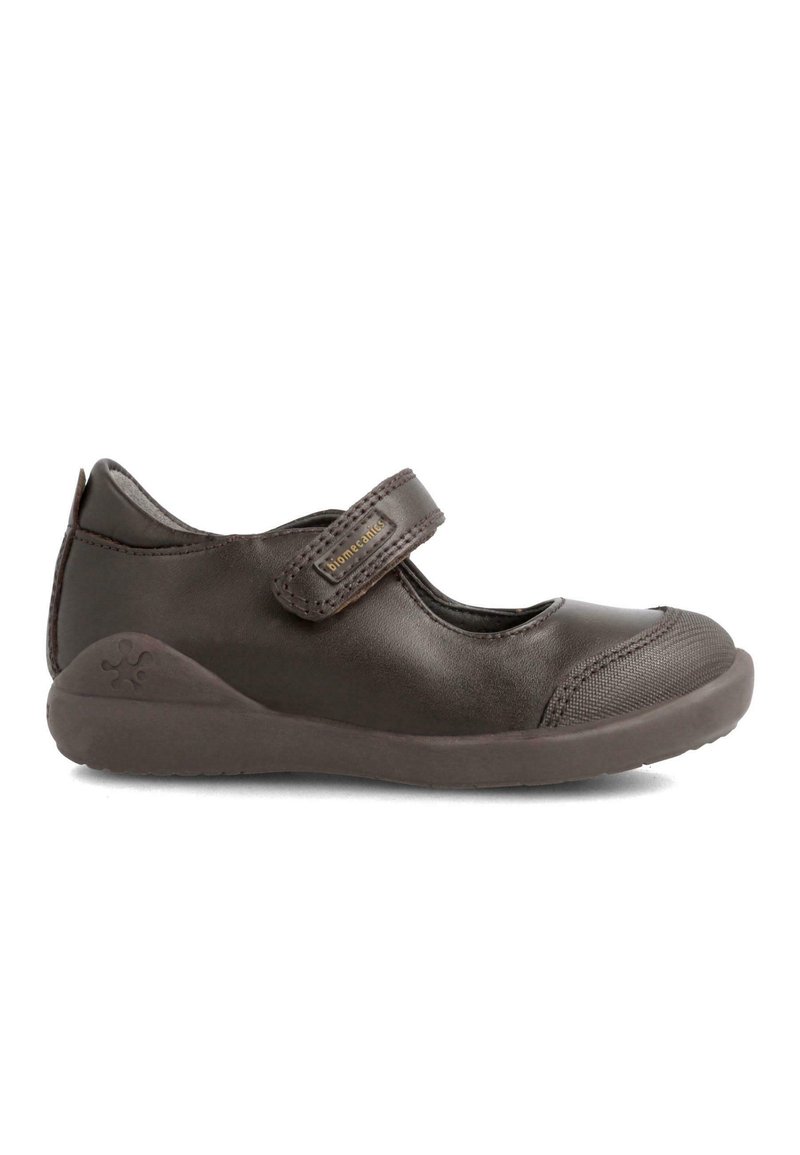 Zapato Mary Jane de cuero marrón con una correa de velcro, puntera redondeada y tapa de puntera texturizada. Presenta una suela de goma y un logotipo grabado en el talón.