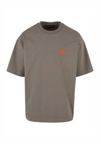 Camiseta gris de manga corta con cuello redondo; presenta un logo bordado en naranja en el lado izquierdo del pecho; fabricada en suave tejido de algodón.