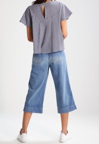 Blå och vit rutigt topp med korta ärmar, med en nyckelhålskärning i ryggen. Parat med vida blå denim culotter och vita sneakers.