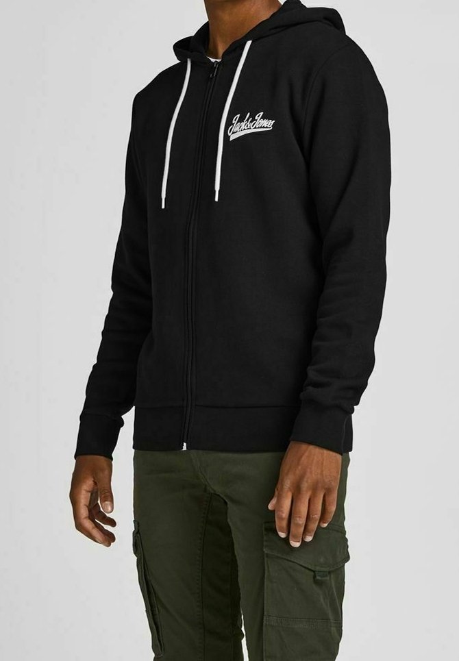 Sort zip-up hoodie med et hvidt logo, snøre i hætten, ribbede manchetter og lommer. Bæres med grøn cargo-bukser.