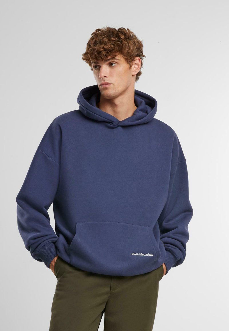 Marineblauwe hoodie van een zachte stof, met een voorzak, verstelbare trekkoordkap en geborduurde tekst aan de zoom.