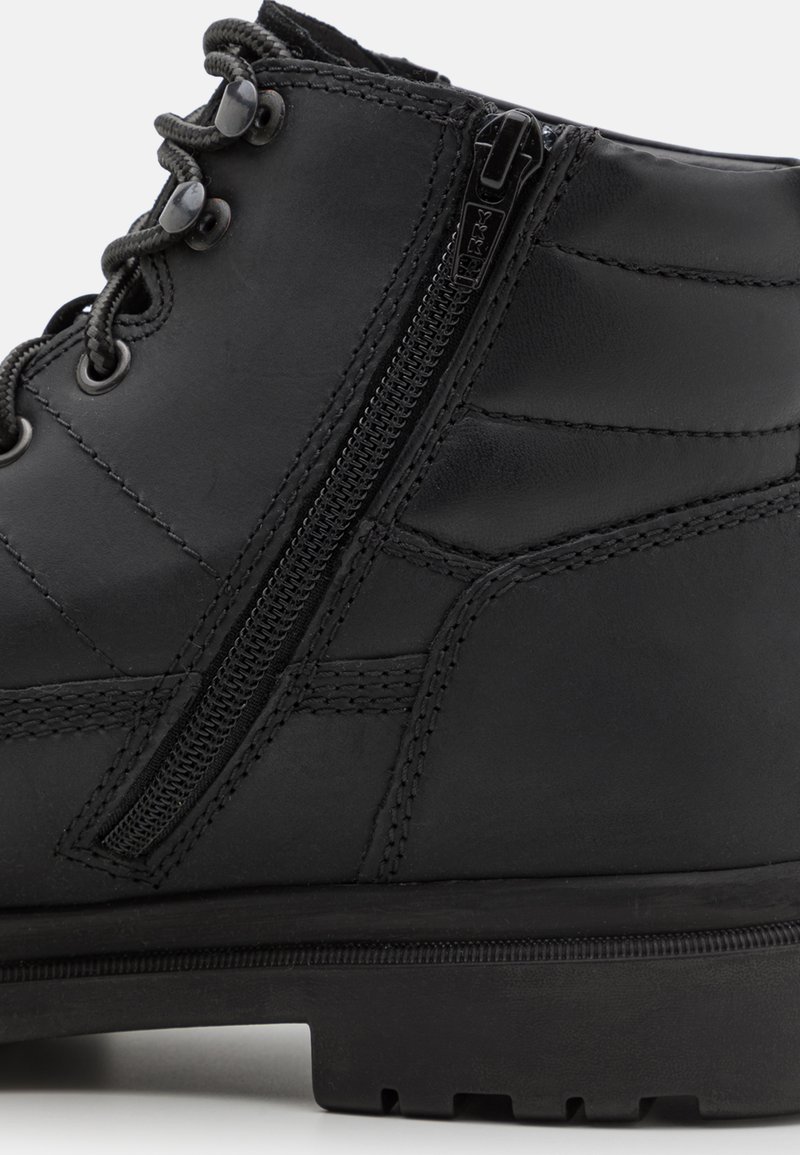 Schwarze Lederstiefel mit strukturierter Oberfläche, ausgestattet mit Metallösen, kontrastierenden Nähten und einem seitlichen Reißverschluss für einen einfachen Zugang.