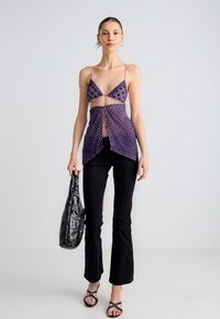 Lilla täpiline võrkmuster ees sügava dekolteega, sobitatud mustade lehvipõlvikutega. Aksessuaarideks must kott ja rihmikud sandaalid.