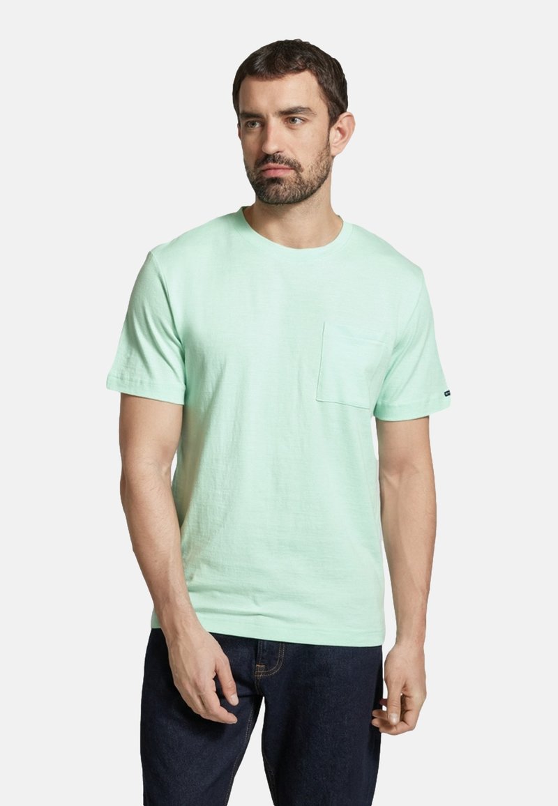 Tricou scurt mint, dintr-un material moale, cu un buzunar pe piept și guler rotund; asortat cu blugi închisi.