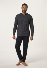 Chemise à rayures bleu marine à manches longues et col en V pour homme, accompagnée de pantalons ajustés bleu marine unis. Les deux sont en tissu doux. Les pantalons ont des poches latérales.