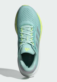 Scarpa sportiva azzurro chiaro con tomaia in rete, accenti gialli e logo grigio. Presenta lacci tondi e suola imbottita per il comfort.