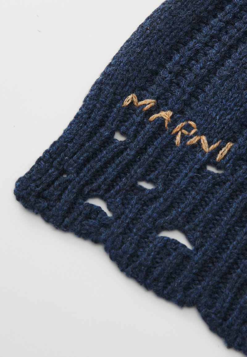 Marineblauwe gebreide stof met verticale ribbels en beige geborduurde tekst "MARAI" op een witte achtergrond.