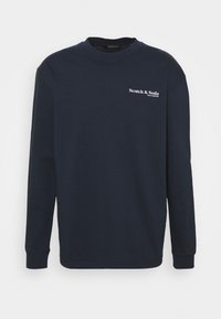 Navy blue long-sleeve shirt featuring a crew neck and white "Scotch & Soda" logo on the chest. Made of cotton with a smooth texture.