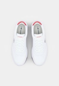 Sneaker in pelle bianca con una texture liscia, dotate di dettagli rossi sul tallone e logo sul linguetta e sul lato. Inclusi i lacci piatti.