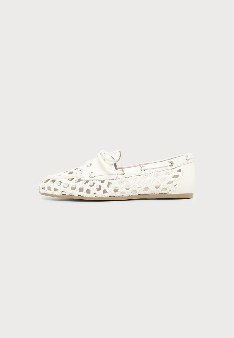 Mocassin en cuir tissé blanc avec motif découpé, détail de lacets autour du col et semelle plate marron clair, vu de profil.