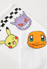 Calcetines blancos con personajes de Pokémon bordados: Pikachu (amarillo), Charmander (naranja) y Gengar (púrpura), con un patrón de punto de ajedrez.