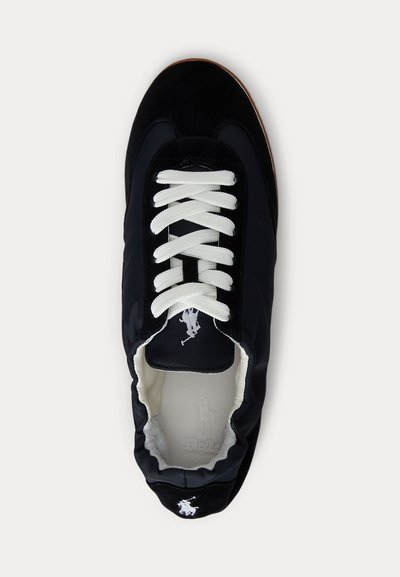 Fekete sportcipő fehér fűzőkkel, lekerekített orral és Polo Ralph Lauren logóval a nyelvén és a sarokpánton, felülről nézve.