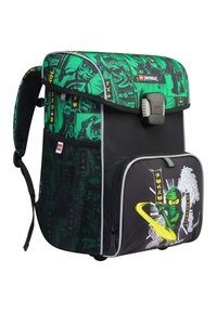 Rucsac din țesătură verde, cu grafică ninja, buzunar inferior negru, bordură gri, bretele căptușite și închidere cu cataramă frontală.