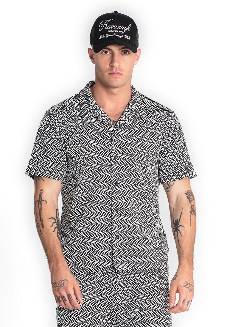 Kurzarm-Hemd mit Knöpfen in Schwarz mit weißem geometrischem Muster; kombiniert mit einer schwarzen Kappe mit weißen Text- und Logodetails.