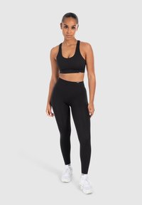 Set di reggiseno sportivo e leggings neri realizzato in tessuto elasticizzato. Il reggiseno ha spalline larghe e scollatura rotonda; i leggings presentano una vita alta.
