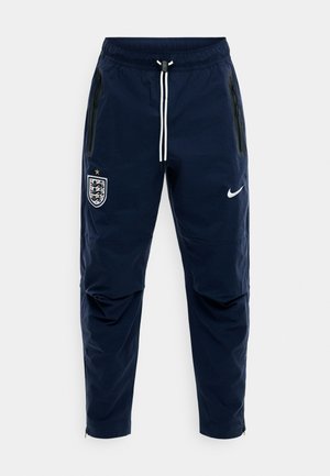 Marineblaue Sporthose mit weißem Kordelzug, seitlichen Reißverschlusstaschen, England-Fußballwappen am linken Oberschenkel und weißem Nike-Swoosh am rechten Oberschenkel.