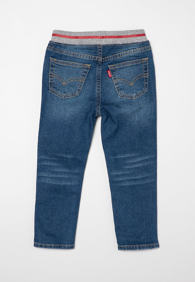 Jeans de mezclilla azul oscuro con una cinturilla elástica a rayas grises y rojas, cinco bolsillos y detalles desgastados en los muslos.