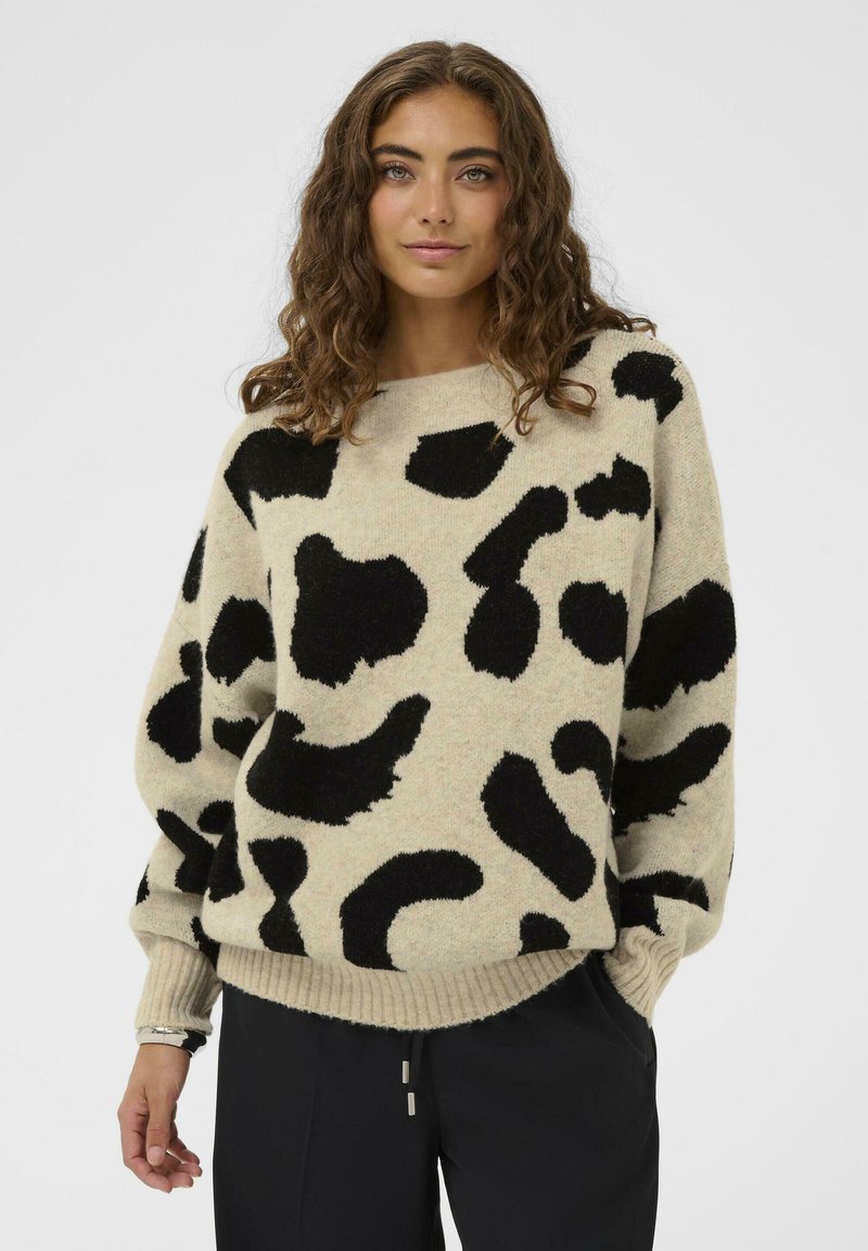 Beidzis džemperis ar melnu abstraktu leopardu rakstu, pārspīlēta piegriezuma, ribinātām piedurknēm un apakšmalai, mīksta tekstūra, minimālistisks dizains.