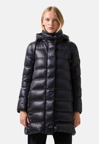 Doudoune noire avec une finition brillante, design à coutures verticales, col haut et capuche. Dotée de poches zippées et de cordons de serrage réglables.