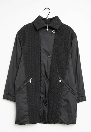Giacca nera con una parte anteriore testurizzata con motivo a zigzag, due tasche con zip e colletto a ribalta. Bottoni frontali e finitura liscia.