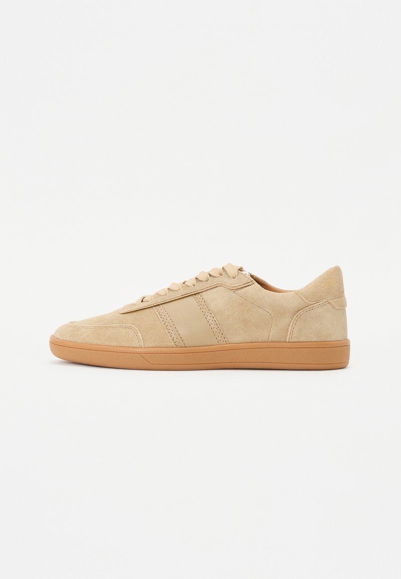 Sneaker in suede beige con punta arrotondata, suola in gomma piatta color tan e design con lacci tonalità. Due strisce verticali sul lato. Branding minimal.