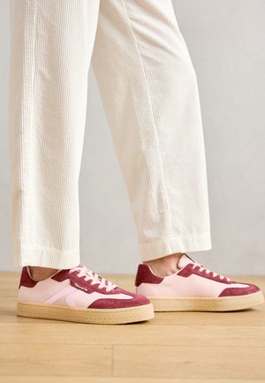 Rosa und burgunderfarbene Sneakers aus Wildleder und glattem Material, mit einer dicken Gummisohle und Schnürung mit strukturierten Akzenten.