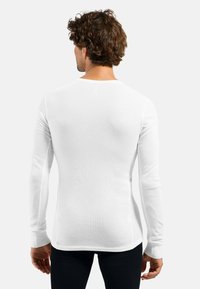 White long-sleeve shirt with a fitted design, smooth texture, and tapered cuffs. Features a crew neck and subtle seam detail.