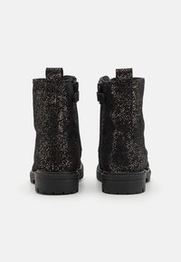 Černé kotníkové boty s texturovaným povrchem, zdobené zlatými skvrnami, bočním zipem a pevnou černou gumovou podrážkou.