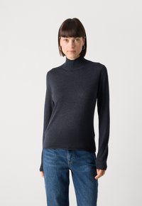 Mørk grå turtleneck genser i myk stoff med lange ermer, kombinert med blå denim jeans. Passformen er slim, og teksturen virker glatt.