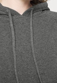 Sweat à capuche gris avec un tissu doux et texturé, une capuche à cordon de serrage et des détails côtelés au niveau de l'encolure et des poignets.