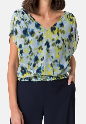 Kortærmet bluse i blå med gul og grøn abstrakt mønster. Har V-hals og indsamlet kant med flæsedetaljer.