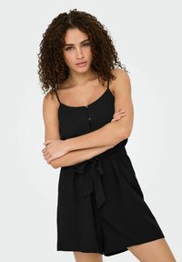 Combi-short sans manches noir avec une coupe décontractée, doté de boutons à l'avant, d'une taille ceinturée et d'un tissu doux.