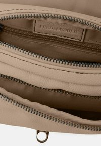 Interno della borsa a tracolla in pelle beige con due scomparti con zip. Materiale a trama fine, hardware in tonalità argento e dettagli con etichetta cucita.