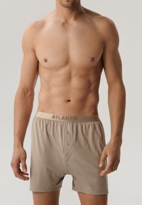 Beżowe bokserki z guzikiem i elastycznym pasem, z logo "ATLANTIC". Miękka tkanina, prosty krój i gładka faktura.