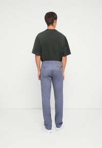 Conjunto masculino que incluye una camisa negra de manga corta y pantalones en tono azul claro. La camisa tiene un corte relajado, mientras que los pantalones cuentan con bolsillos traseros.
