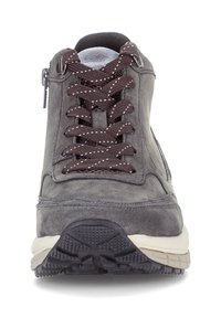 Grijze suède sneakerversie met zwart-witte gepatternde veters, dikke crèmekleurige zool en zijrits, gezien vanuit het front.