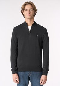 Maglione zip-up nero con maniche lunghe, realizzato in un materiale a maglia testurizzata, con un piccolo logo sul petto e polsini a coste.